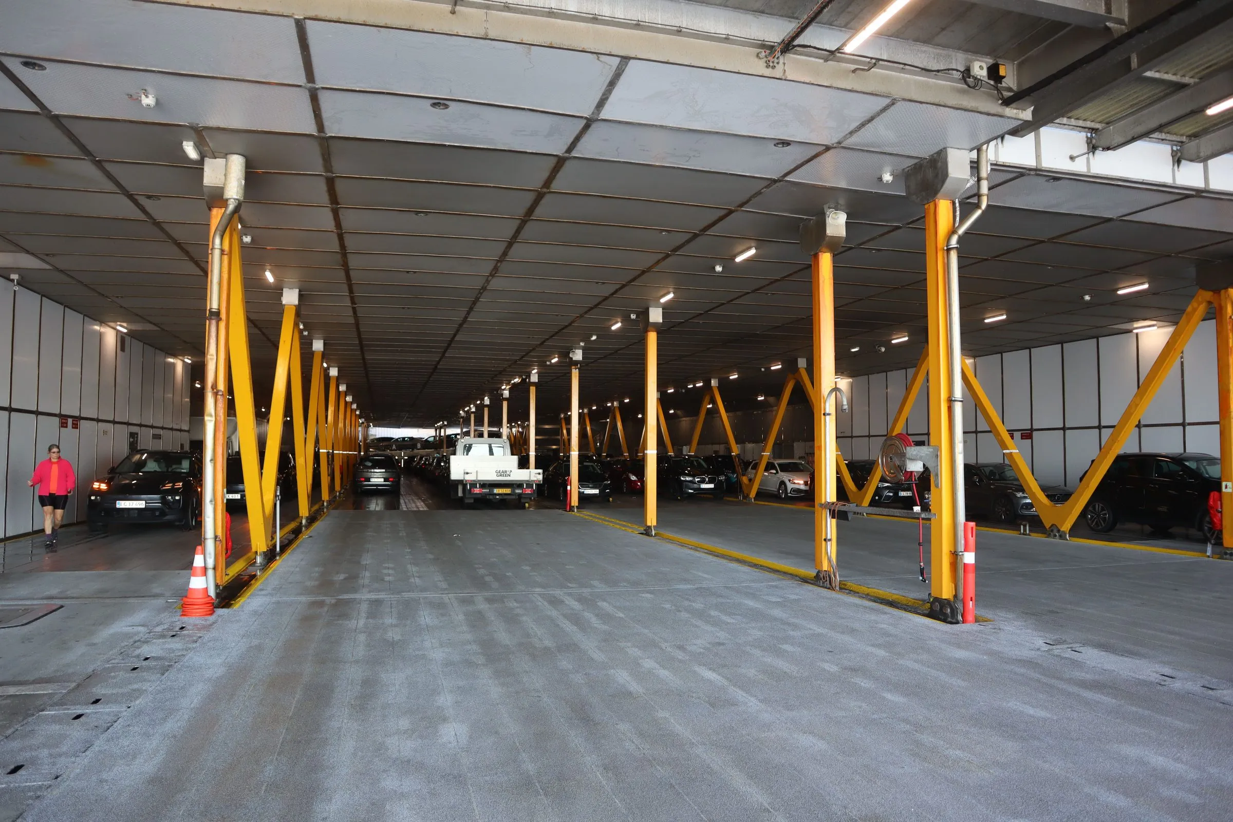The empty car deck of the ferry with yellow steel supports along the lanes