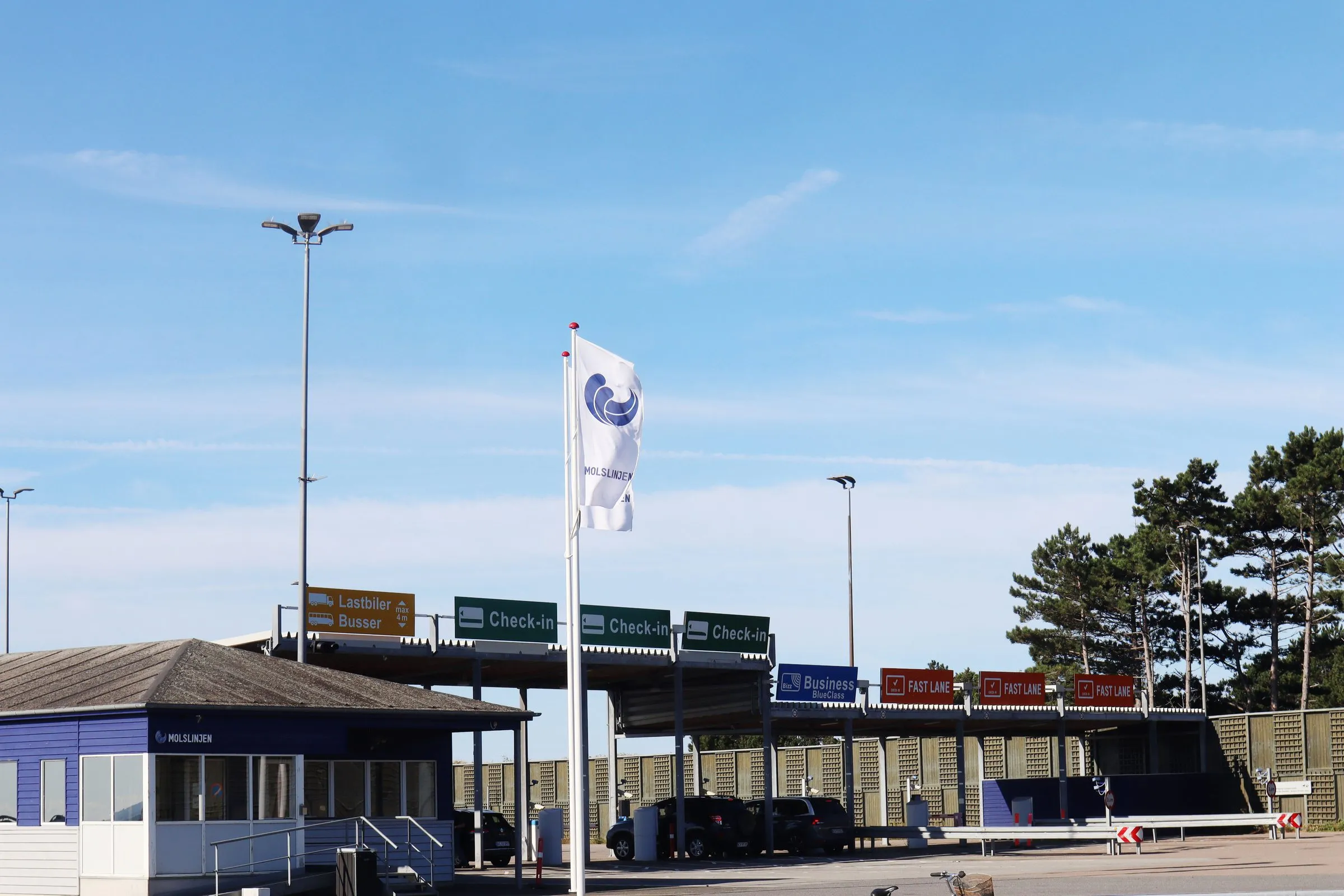 Check-in-huse under en overdækning ved Molslinjens færgeterminal med rederiets flag